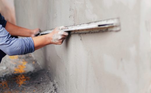 Concrete plasterers to create industrial workers background walls with plastering tools.